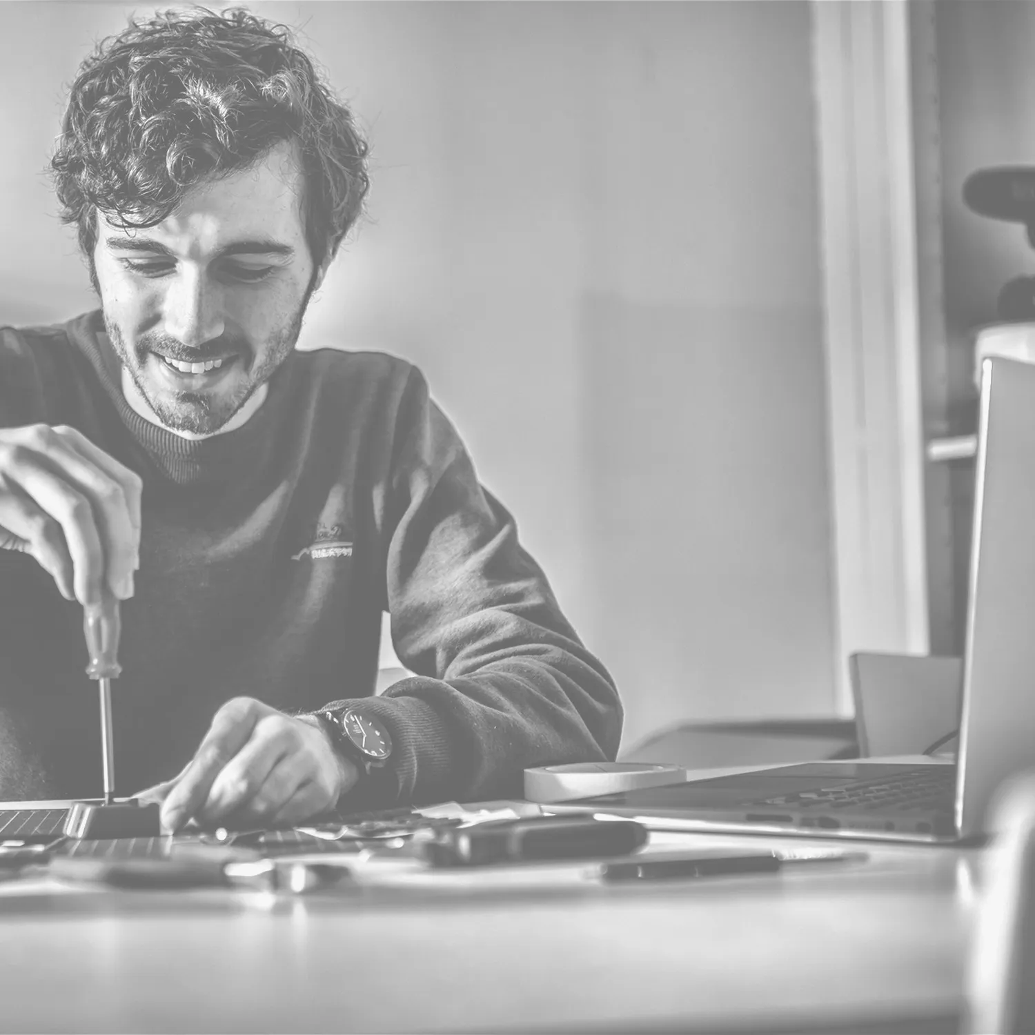 Nyckle at his desk, assembling a LITTA solar bike light with a screwdriver